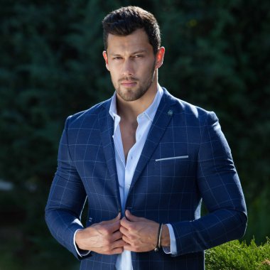 Dışarıda poz veren zarif yakışıklı genç adam..