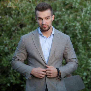 Dışarıda poz veren zarif yakışıklı genç adam..