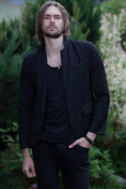 Dışarıda poz veren zarif yakışıklı genç adam..