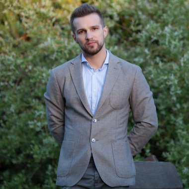 Dışarıda poz veren zarif yakışıklı genç adam..