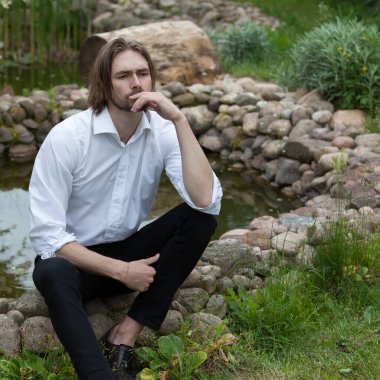 Dışarıda poz veren zarif yakışıklı genç adam..