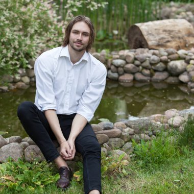 Dışarıda poz veren zarif yakışıklı genç adam..