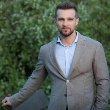 Dışarıda poz veren zarif yakışıklı genç adam..