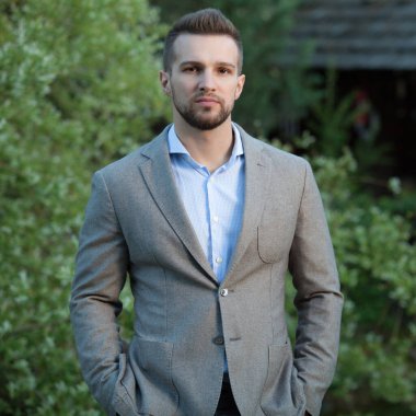 Dışarıda poz veren zarif yakışıklı genç adam..