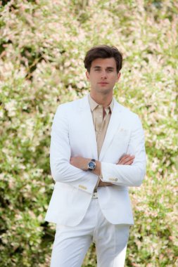 Dışarıda poz veren zarif yakışıklı genç adam..