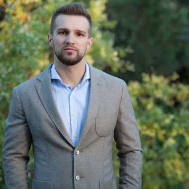 Dışarıda poz veren zarif yakışıklı genç adam..