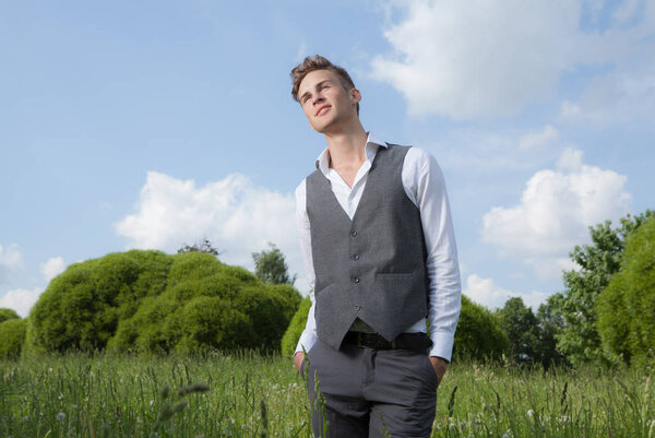 Молодой элегантный красивый мужчина позирует снаружи
.