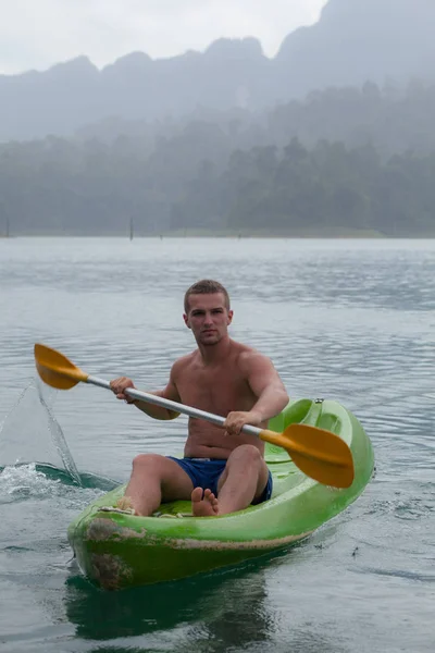 Junger Sportler paddelt im See. — Stockfoto