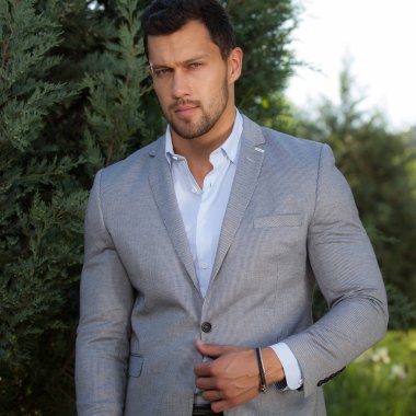 Dışarıda poz veren zarif yakışıklı genç adam..