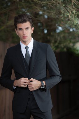 Dışarıda poz veren zarif yakışıklı genç adam..