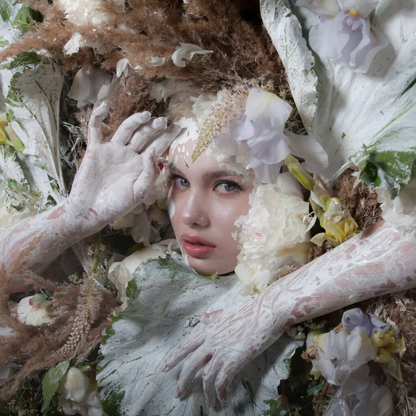 Portrait féminin dans une stylisation de conte de fées entouré de plantes et de fleurs naturelles . — Photo