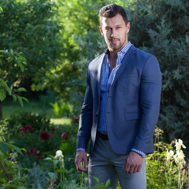 Dışarıda poz veren zarif yakışıklı genç adam..