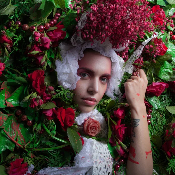 Vrouwelijk portret in sprookjesachtige stylization omgeven met natuurlijke bloemen. — Stockfoto