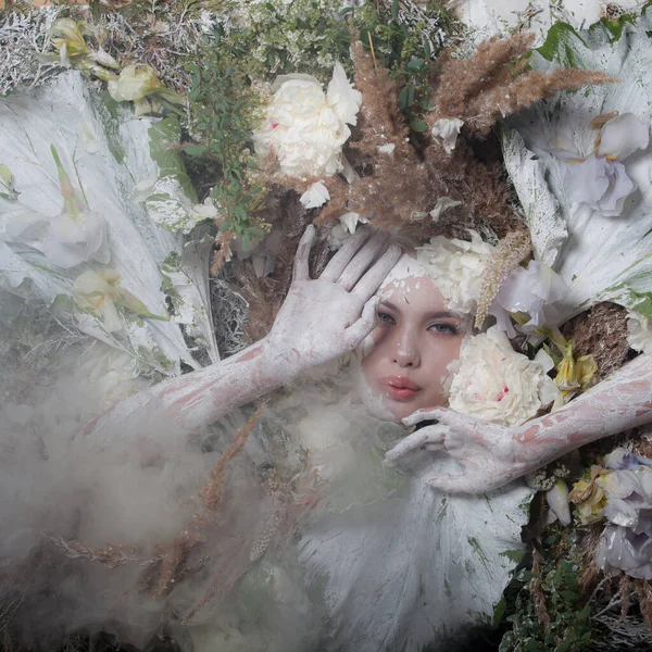 Portrait féminin dans une stylisation de conte de fées entouré de plantes et de fleurs naturelles . — Photo