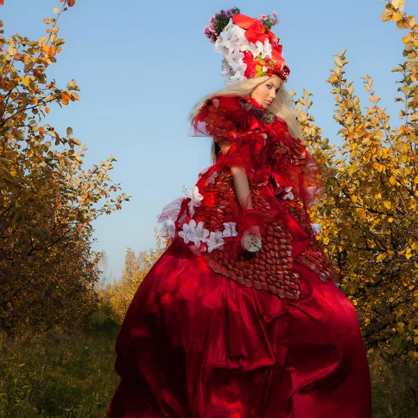 Sensuale ragazza bionda in fantasia rosso fiaba stilizzazione nel parco delle mele . — Foto Stock