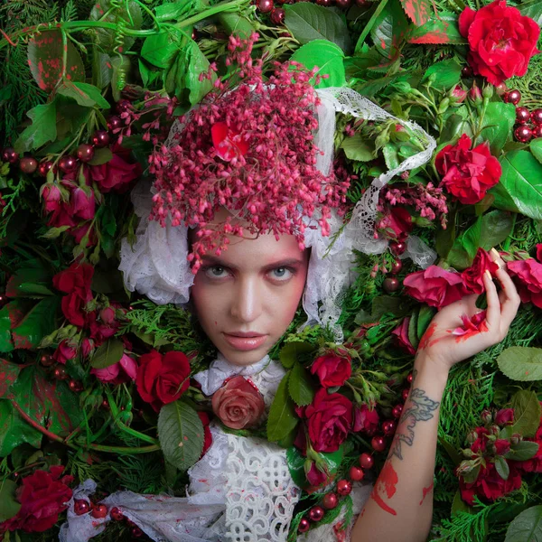 Vrouwelijk portret in sprookjesachtige stylization omgeven met natuurlijke bloemen. — Stockfoto