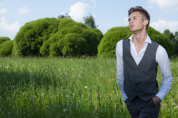 Молодой элегантный красивый мужчина позирует снаружи
.