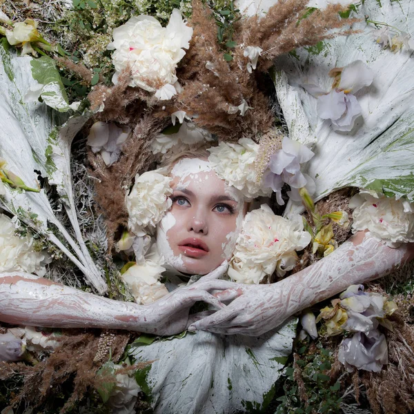 Vrouwelijk portret in sprookjesachtige stijl omgeven door natuurlijke planten en bloemen. — Stockfoto