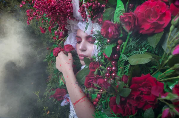 Vrouwelijk portret in sprookjesachtige stylization omgeven met natuurlijke bloemen. — Stockfoto