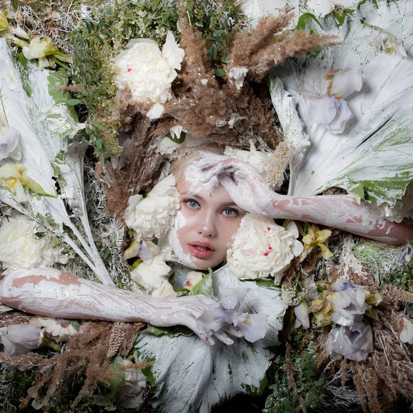 Portret kobiety w bajkowej stylizacji otoczonej naturalnymi roślinami i kwiatami. — Zdjęcie stockowe