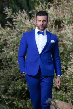 Dışarıda poz veren zarif yakışıklı genç adam..