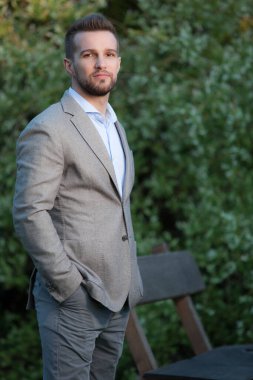 Dışarıda poz veren zarif yakışıklı genç adam..