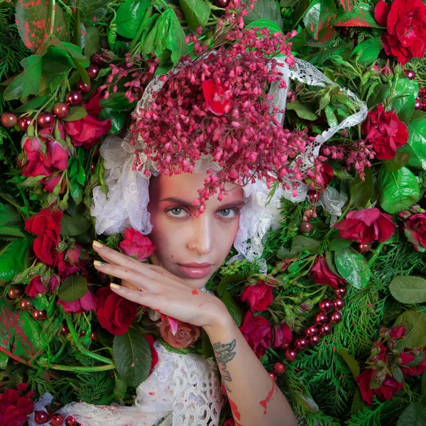 Vrouwelijk portret in sprookjesachtige stylization omgeven met natuurlijke bloemen. — Stockfoto