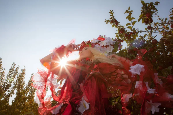 Sensuale ragazza bionda in fantasia rosso fiaba stilizzazione nel parco delle mele . — Foto Stock