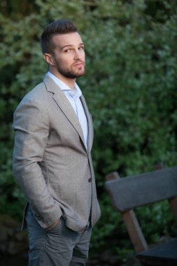 Dışarıda poz veren zarif yakışıklı genç adam..