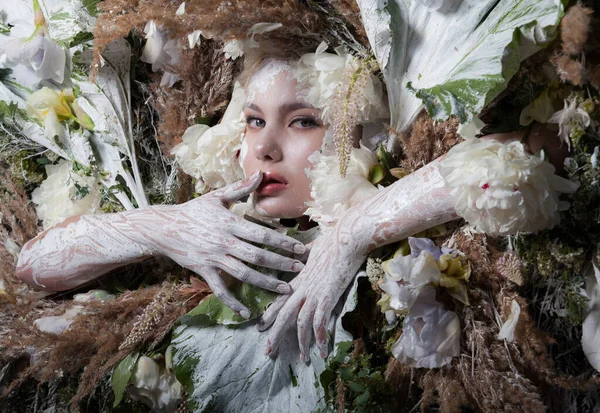 Vrouwelijk portret in sprookjesachtige stijl omgeven door natuurlijke planten en bloemen. — Stockfoto