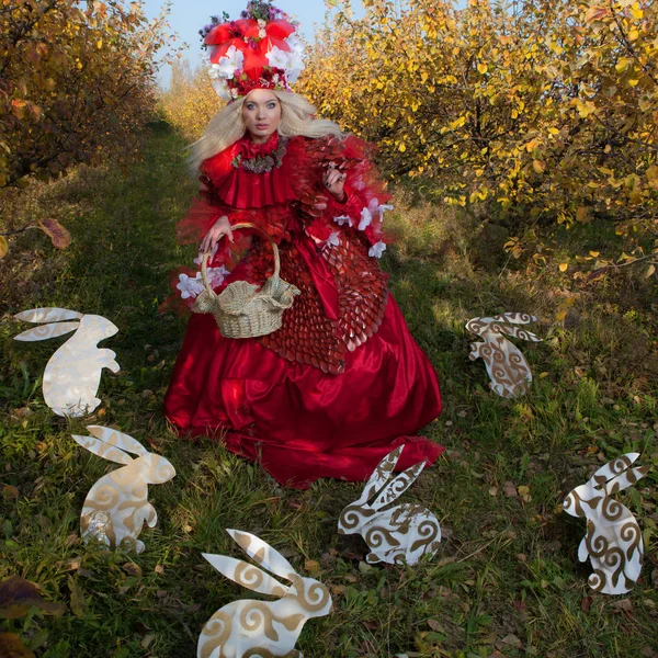 Sinnliches blondes Mädchen in Fantasy-roter Märchenstilisierung im Apfelpark. — Stockfoto