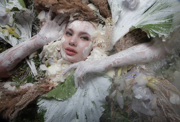 Retrato feminino em estilo conto de fadas rodeado de plantas e flores naturais . — Fotografia de Stock