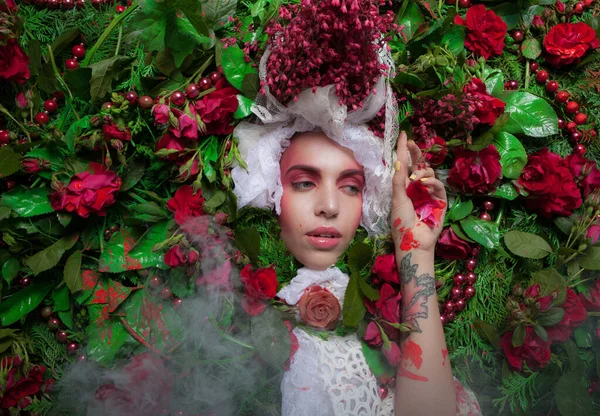 Vrouwelijk portret in sprookjesachtige stylization omgeven met natuurlijke bloemen. — Stockfoto