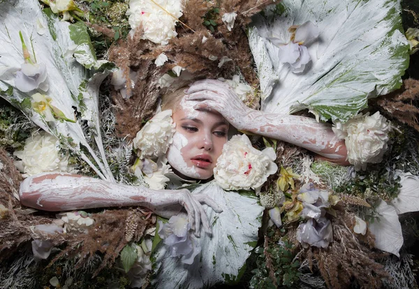 Retrato feminino em estilo conto de fadas rodeado de plantas e flores naturais . — Fotografia de Stock