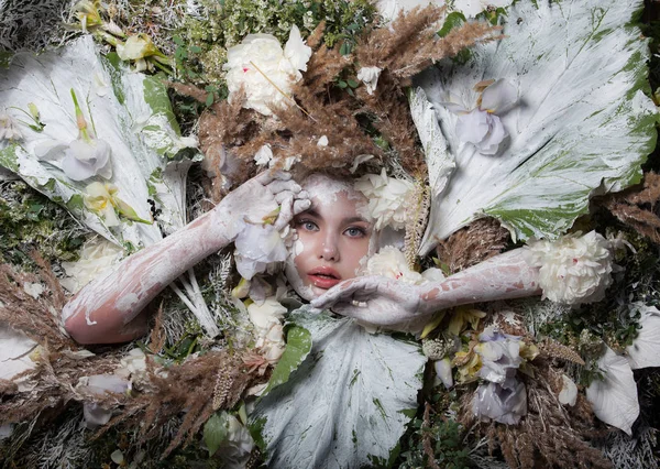 Retrato feminino em estilo conto de fadas rodeado de plantas e flores naturais . — Fotografia de Stock