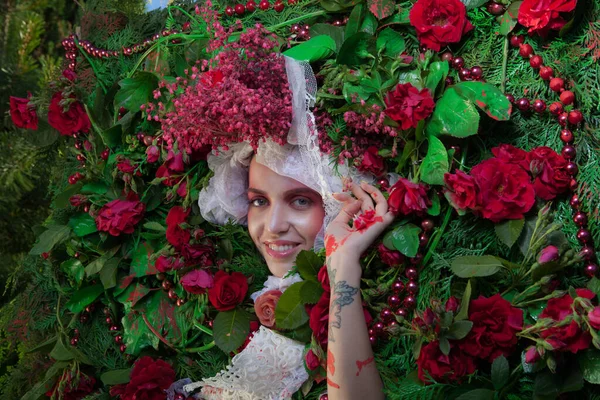 Vrouwelijk portret in sprookjesachtige stylization omgeven met natuurlijke bloemen. — Stockfoto