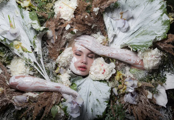 Retrato feminino em estilo conto de fadas rodeado de plantas e flores naturais . — Fotografia de Stock