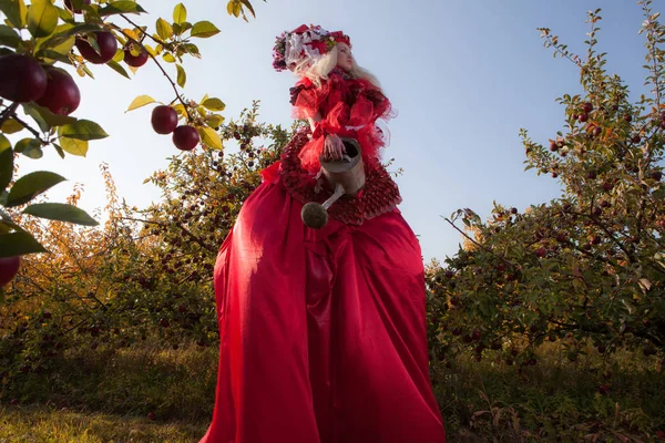 Sinnliches blondes Mädchen in Fantasy-roter Märchenstilisierung im Apfelpark. — Stockfoto