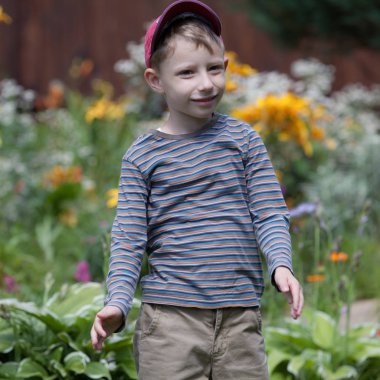 Dışarıda sevimli sarı saçlı bir çocuk oynuyor..