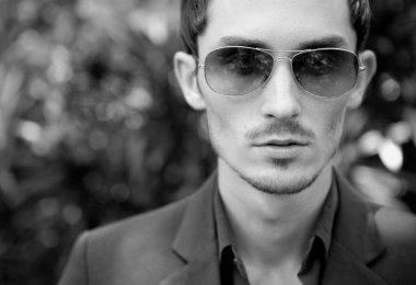 Dışarıda poz veren zarif yakışıklı genç adam..