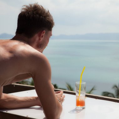 Tropikal manzaraya karşı gevşek, çekici genç bir adam..