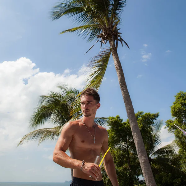 Tropikal manzaraya karşı gevşek, çekici genç bir adam..