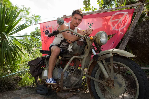 Ontspannen aantrekkelijke jongeman tegen tropisch landschap. — Stockfoto