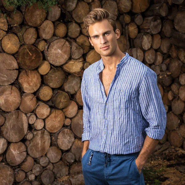 Young handsome man in casual shirt poses near wooden background. — Stock Photo, Image