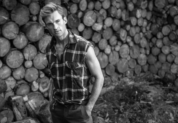 Ein junger gutaussehender Mann in lässigem Hemd posiert in der Nähe des Holzuntergrunds. Schwarz-Weiß-Foto. — Stockfoto