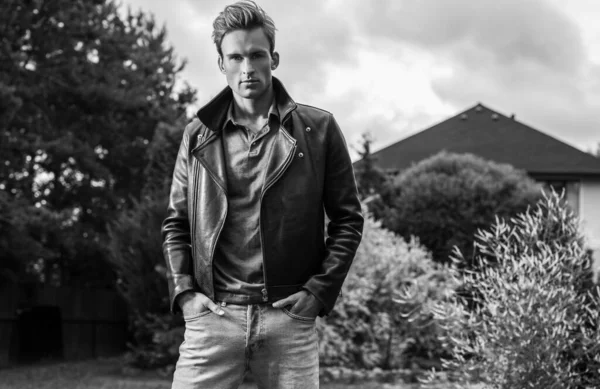 Young handsome man in classic leather jacket pose in summer garden. Black-white photo. — Stock Photo, Image