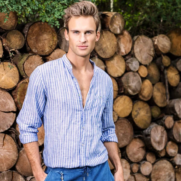 Ung stilig man i casual shirt poserar nära trä bakgrund. — Stockfoto