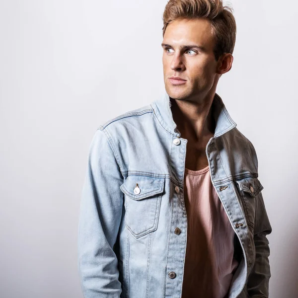 Schöner junger Mann in Jeansjacke posiert im Studio. — Stockfoto
