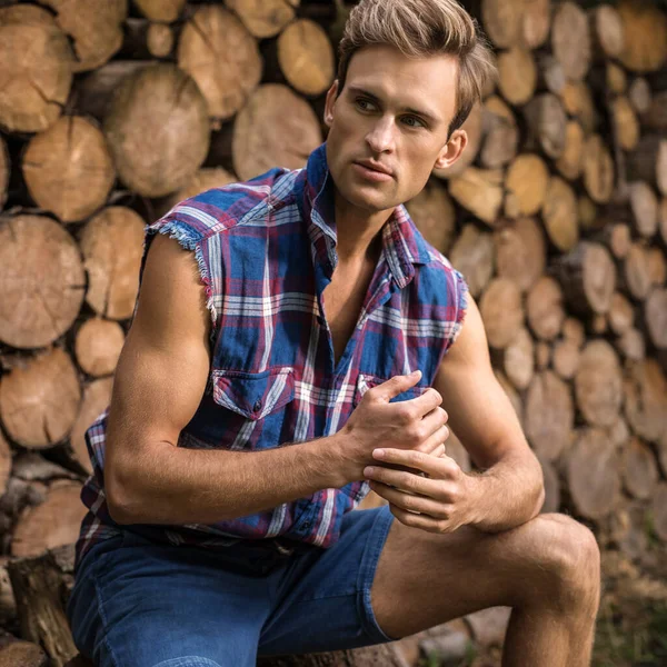 Joven hombre guapo en camisa casual posa cerca de fondo de madera . — Foto de Stock