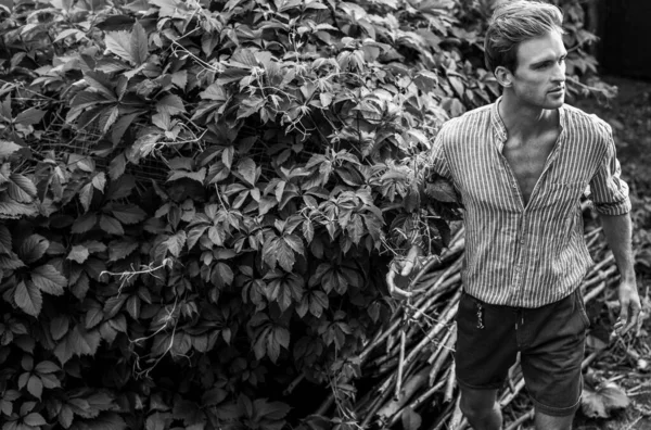 Joven hombre guapo en ropa casual posan en el jardín de verano. Foto en blanco y negro . — Foto de Stock